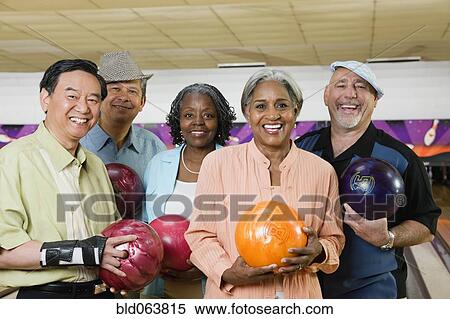 Stock Photography - Friends holding bowling balls in bowling alley. Fotosearch