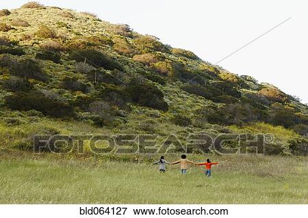 Stock Photo - Friends holding hands in rural field. Fotosearch