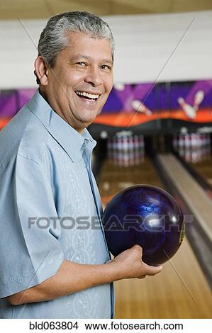 Picture - Hispanic man holding bowling ball. Fotosearch