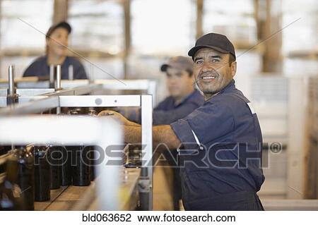 Stock Image - Hispanic man working in bottling factory. Fotosearch