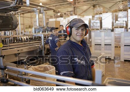 Stock Photo - Hispanic man working in bottling factory. Fotosearch