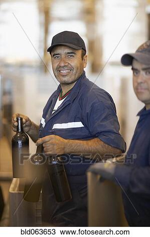 Stock Image - Hispanic men working in bottling factory. Fotosearch