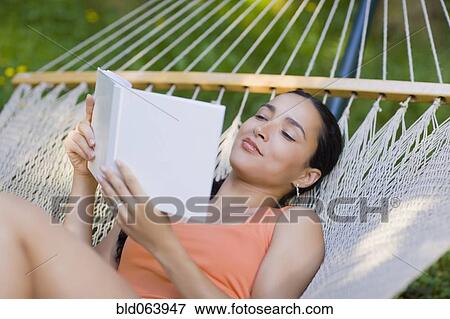 Stock Photo - Hispanic woman laying in hammock reading. Fotosearch