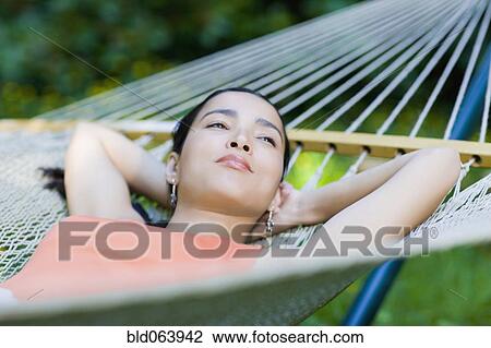 Stock Image - Hispanic woman laying in hammock. Fotosearch