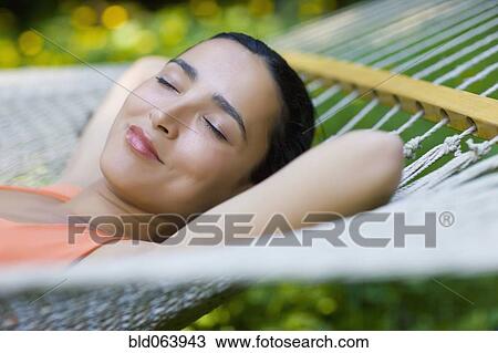 Stock Image - Hispanic woman laying in hammock. Fotosearch
