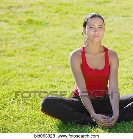 Stock Photo - Hispanic woman stretching in grass. Fotosearch