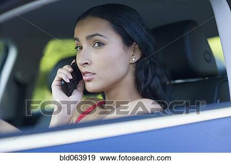 Stock Photo - Hispanic woman talking on cell phone while driving. Fotosearch