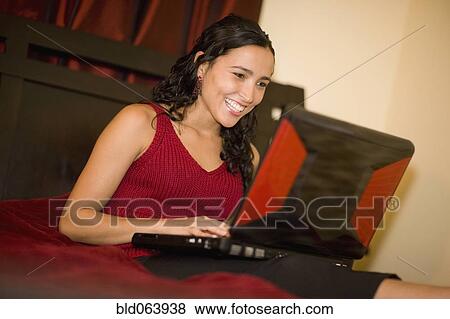 Hispanic woman using laptop in bed View Large Photo Image Stock Photo - Hispanic woman using laptop in bed. Fotosearch