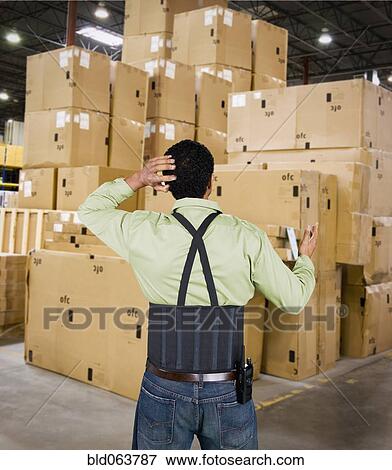 Stock Photo - Hispanic working confused by large stack of boxes. Fotosearch