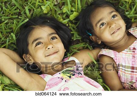 Picture - Indian girls laying in grass. Fotosearch