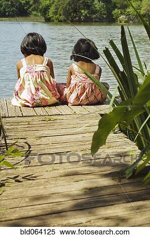 Stock Photography - Indian girls sitting on dock over lake. Fotosearch