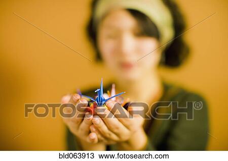 Stock Image - Japanese woman holding origami bird. Fotosearch