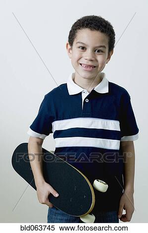 Stock Photography - Mixed race boy holding skateboard. Fotosearch