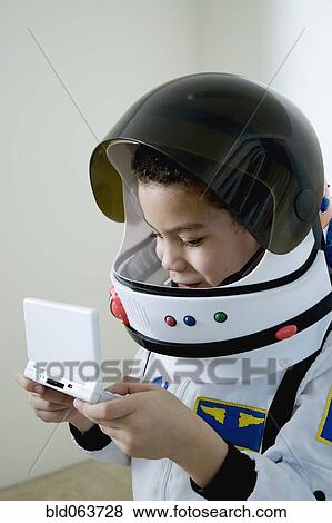 Stock Photo - Mixed race boy in astronaut costume with video game. Fotosearch
