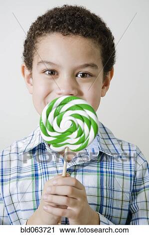 Stock Image - Mixed race boy with oversized lollipop. Fotosearch