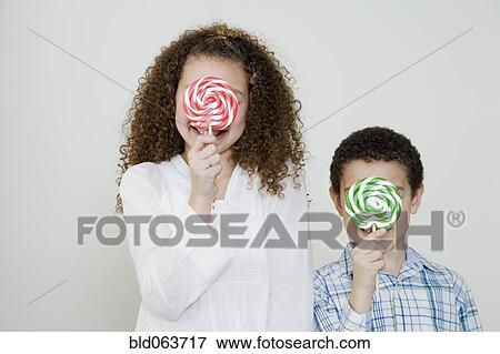Stock Photo - Mixed race brother and sister with oversized lollipops. Fotosearch