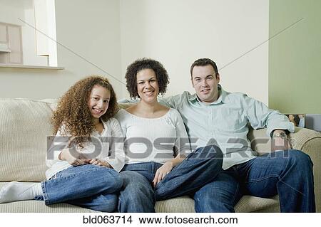 Mixed race family sitting on sofa and smiling View Large Photo Image Picture - Mixed race family sitting on sofa and smiling. Fotosearch