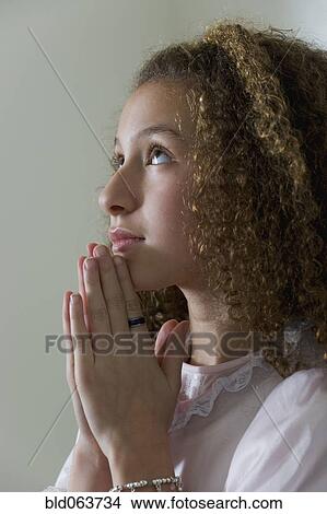 Picture - Mixed race girl in nightgown praying. Fotosearch