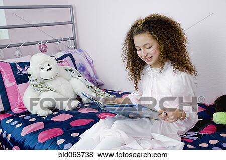 Mixed race girl reading bedtime story View Large Photo Image Stock Photo - Mixed race girl reading bedtime story. Fotosearch
