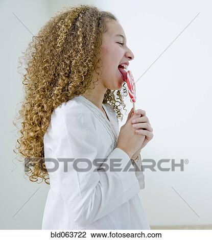 Stock Image - Mixed race girl with oversized lollipop. Fotosearch