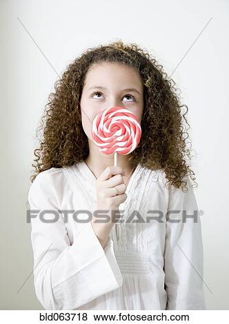 Stock Photo - Mixed race girl with oversized lollipop. Fotosearch