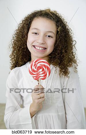 Stock Photo - Mixed race girl with oversized lollipop. Fotosearch