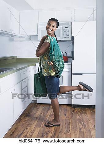 Stock Photograph - Mixed race woman holding reusable grocery bag. Fotosearch