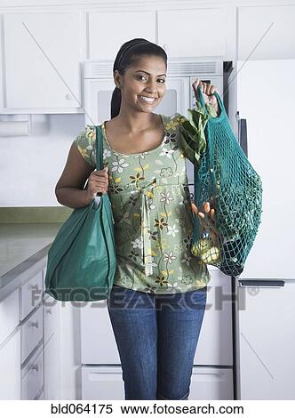 Stock Photography - Mixed race woman holding reusable grocery bag. Fotosearch