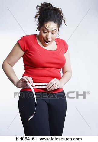 Mixed race woman measuring her waistline View Large Photo Image Stock Image - Mixed race woman measuring her waistline. Fotosearch