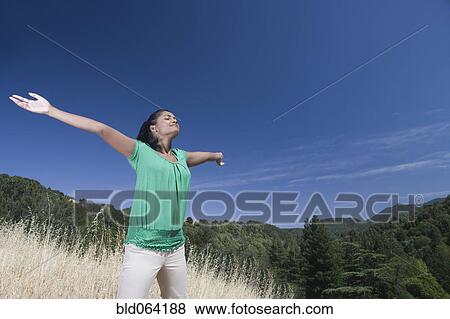 Stock Photo - Mixed race woman outdoors with arms outstretched. Fotosearch