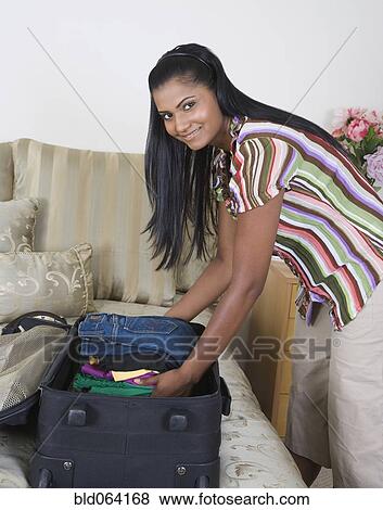 Stock Photo - Mixed race woman packing suitcases. Fotosearch