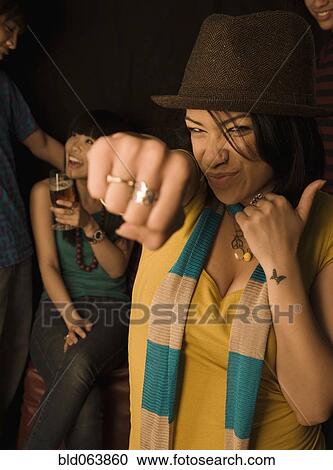 Stock Image - Mixed race woman punching air in nightclub. Fotosearch