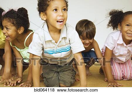 Stock Photo - Multi-ethnic children kneeling and smiling. Fotosearch