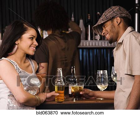 Stock Image - Multi-ethnic couple drinking in nightclub. Fotosearch
