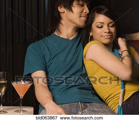 Stock Photo - Multi-ethnic couple drinking in nightclub. Fotosearch