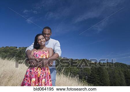 Stock Photography - Multi-ethnic couple hugging in rural area. Fotosearch