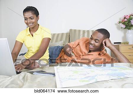 Picture - Multi-ethnic couple looking at map and laptop. Fotosearch