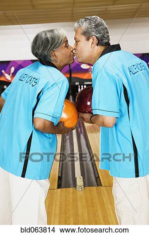 Picture - Multi-ethnic couple on bowling team, kissing. Fotosearch