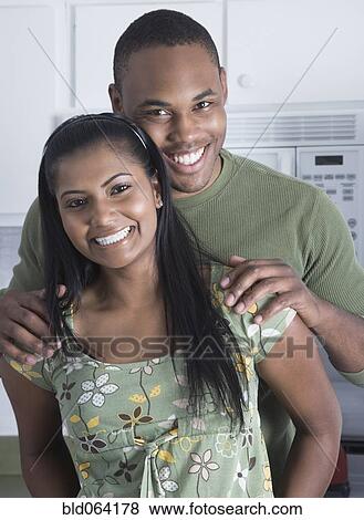 Stock Photo - Multi-ethnic couple standing in kitchen. Fotosearch