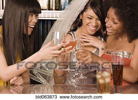 Stock Image - Multi-ethnic friends drinking in nightclub for bachelorette party. Fotosearch