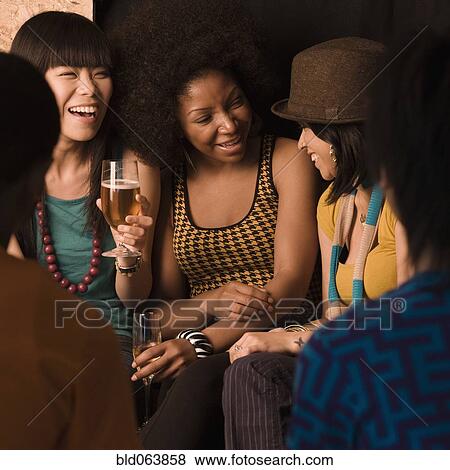 Stock Photo - Multi-ethnic friends drinking in nightclub. Fotosearch