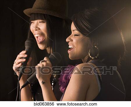 Stock Photograph - Multi-ethnic friends singing karaoke. Fotosearch