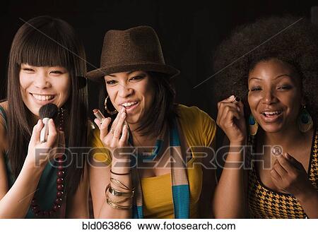 Stock Photograph - Multi-ethnic women putting on makeup. Fotosearch