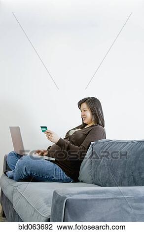 Stock Image - Pregnant Asian woman buying merchandise over the internet. Fotosearch