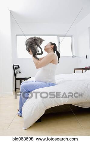 Stock Photo - Pregnant Asian woman holding cat. Fotosearch