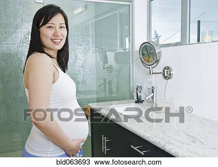 Stock Image - Pregnant Asian woman in bathroom. Fotosearch