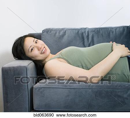 Pregnant Asian woman laying on sofa View Large Photo Image Stock Image - Pregnant Asian woman laying on sofa. Fotosearch