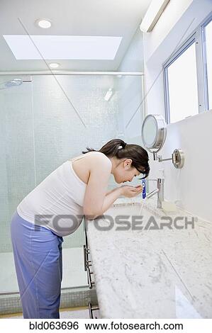 Pregnant Asian woman washing face in bathroom View Large Photo Image Stock Photograph - Pregnant Asian woman washing face in bathroom. Fotosearch