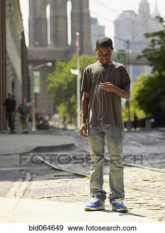 Stock Photo - African boy listening to mp3 player in urban setting. Fotosearch