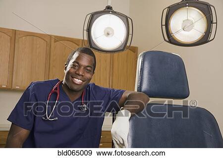 Stock Photo - African dentist next to dentist’s chair. Fotosearch
